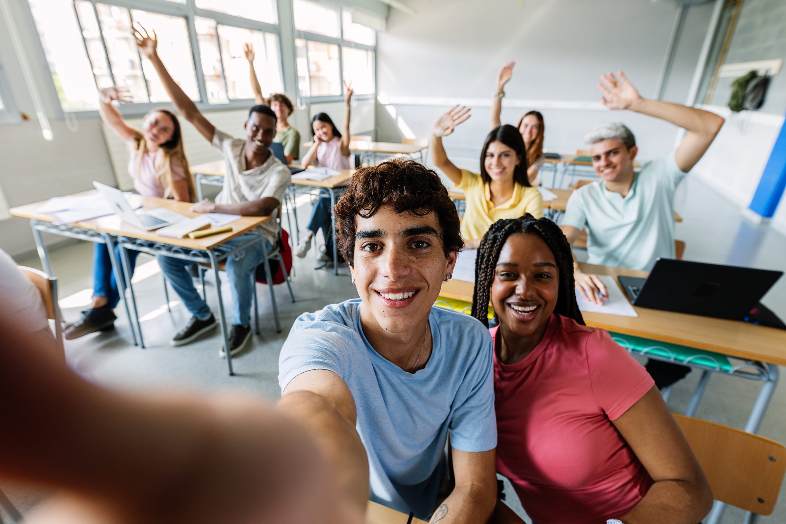 Joyful group of high school students taking selfie during lecture in classroom